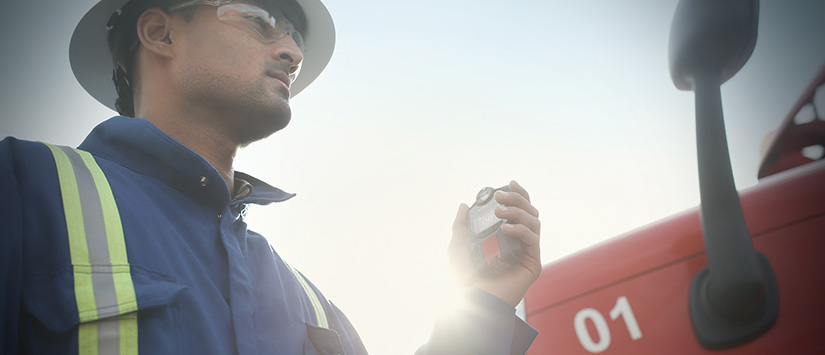 Trabajador de pie junto a un camión con un detector de gas Blackline Safety G7. Banner de 825 x 355.
